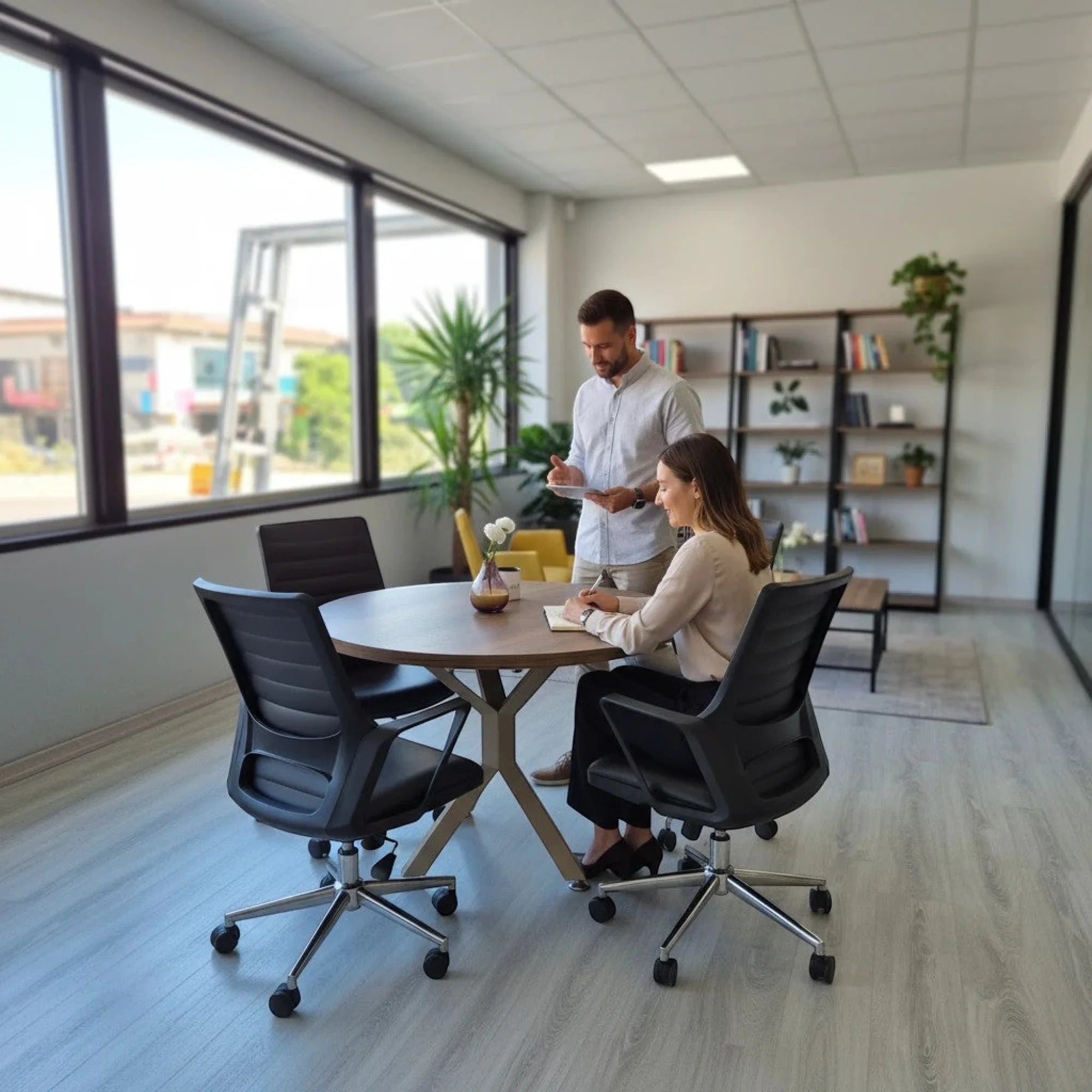 İstanbul Ofis Mobilya modern ahşap yuvarlak toplantı masası, ofiste çalışan iki kişiyle birlikte şık bir çalışma alanı.